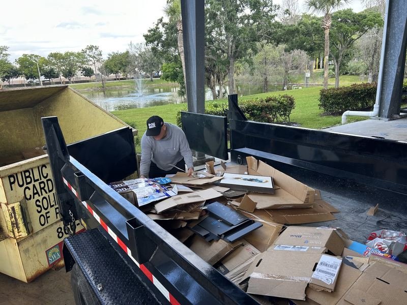 Tyler sorting flattened cardboard into a public recycling container