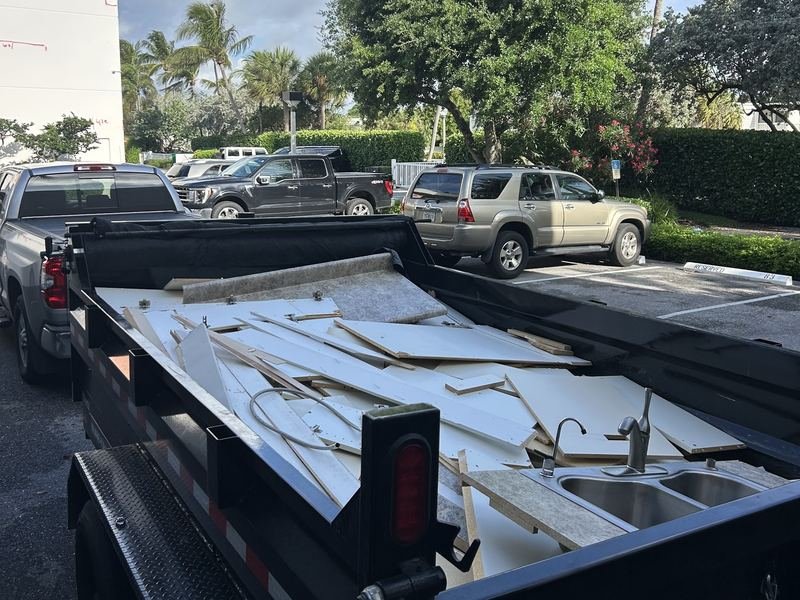 Dump trailer loaded with cabinet panels, countertop and a kitchen sink from a demo job