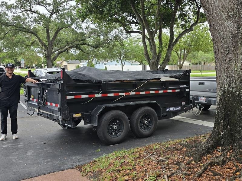 Loaded and tarped dump trailer hitched to the truck, ready to leave the job site